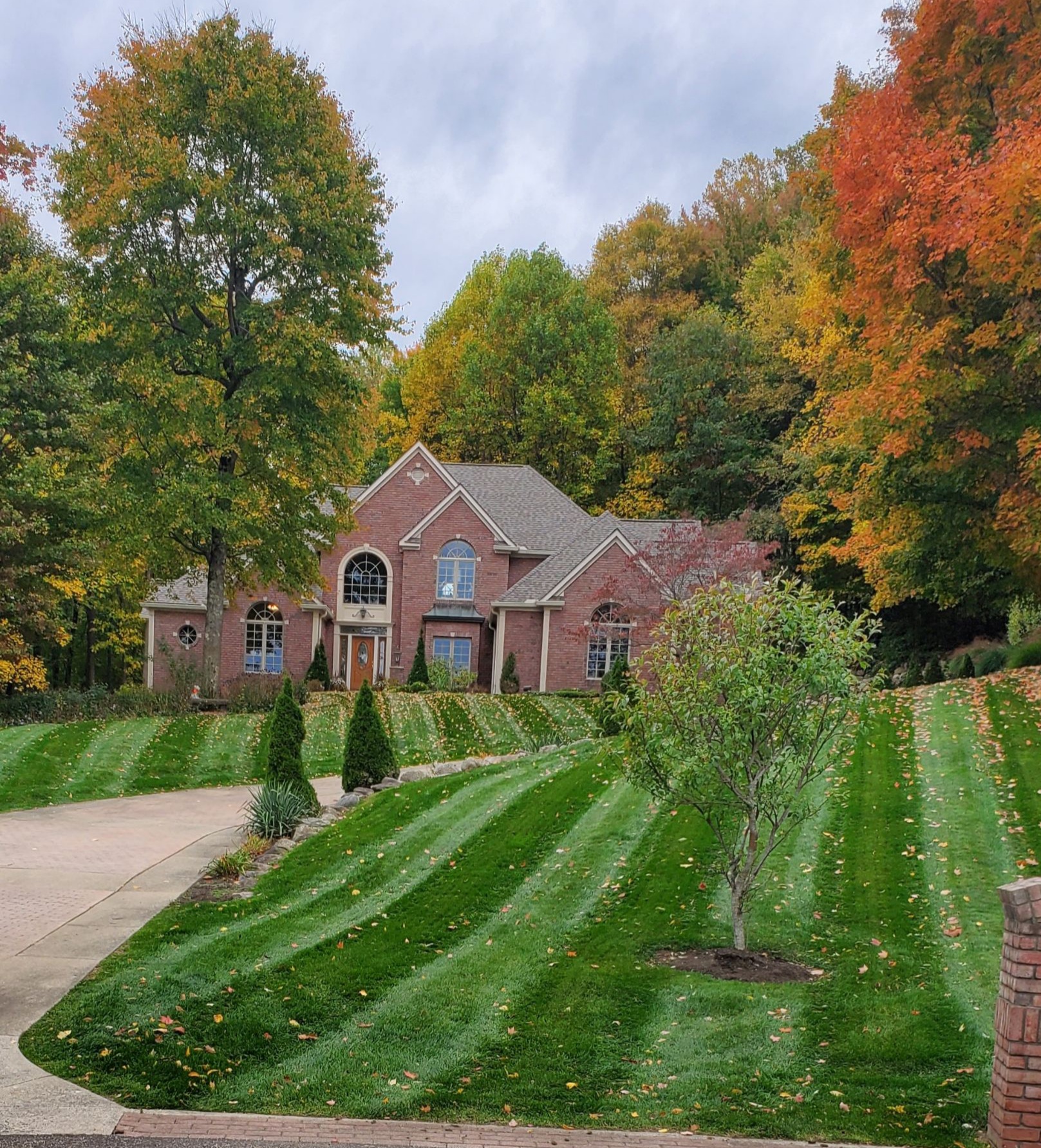 large brick house in fall with plush green lawn